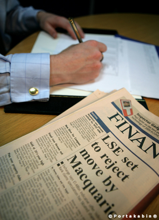 Businessman signing papers with Financial Times in foreground. Conceptual Photography by David Barr